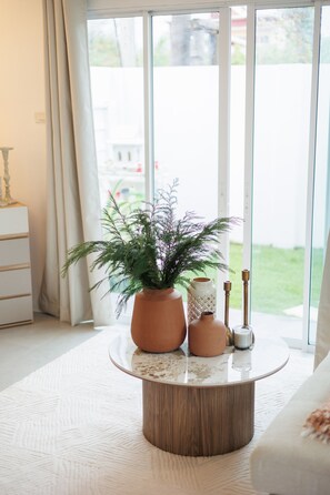 Ein Wohnzimmer mit einem runden Holztisch, einer Topfpflanze und einer Ziervase.