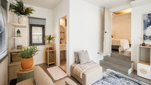 En modern inredning med en soffa, ett soffbord, en trappa som leder upp till ett sovrum och ett badrum som syns genom en öppen dörr.