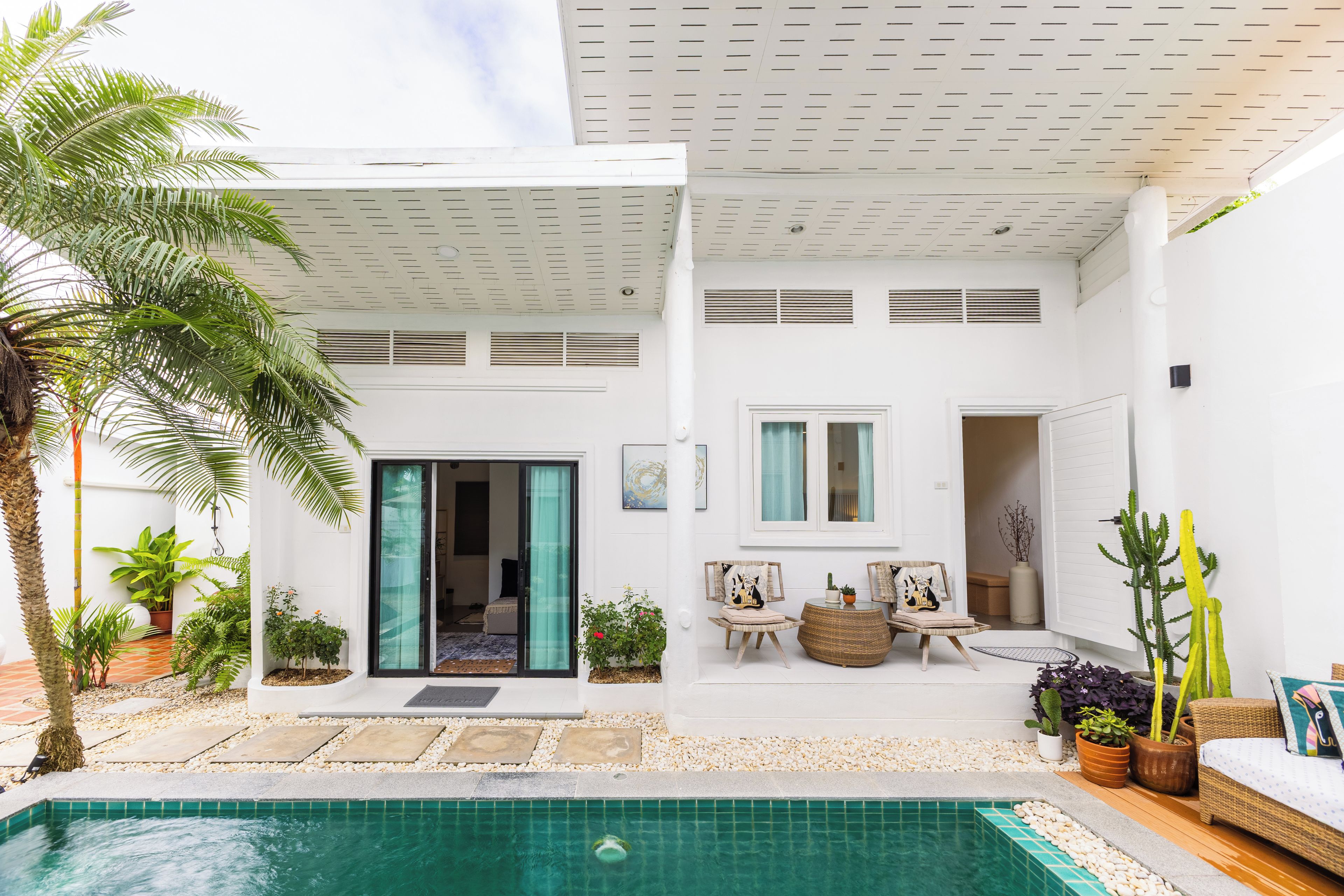 A modern house with a swimming pool, outdoor seating, and various plants.