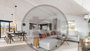 A modern living room with a sofa, ottoman, and dining area with chairs and a table. - Amazing home in Hemmet with sauna (Hemmet)