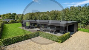 A modern house with a covered patio, a large lawn, and a gravel driveway. - Stunning home in Hemmet with sauna (Hemmet)
