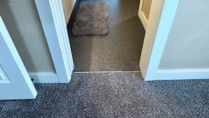 A narrow hallway leading to a bedroom with a bed, a ceiling fan, and a small rug on the floor. - Baldwin Retreat | Spacious Stay w/ 3 King Beds (Meridian)