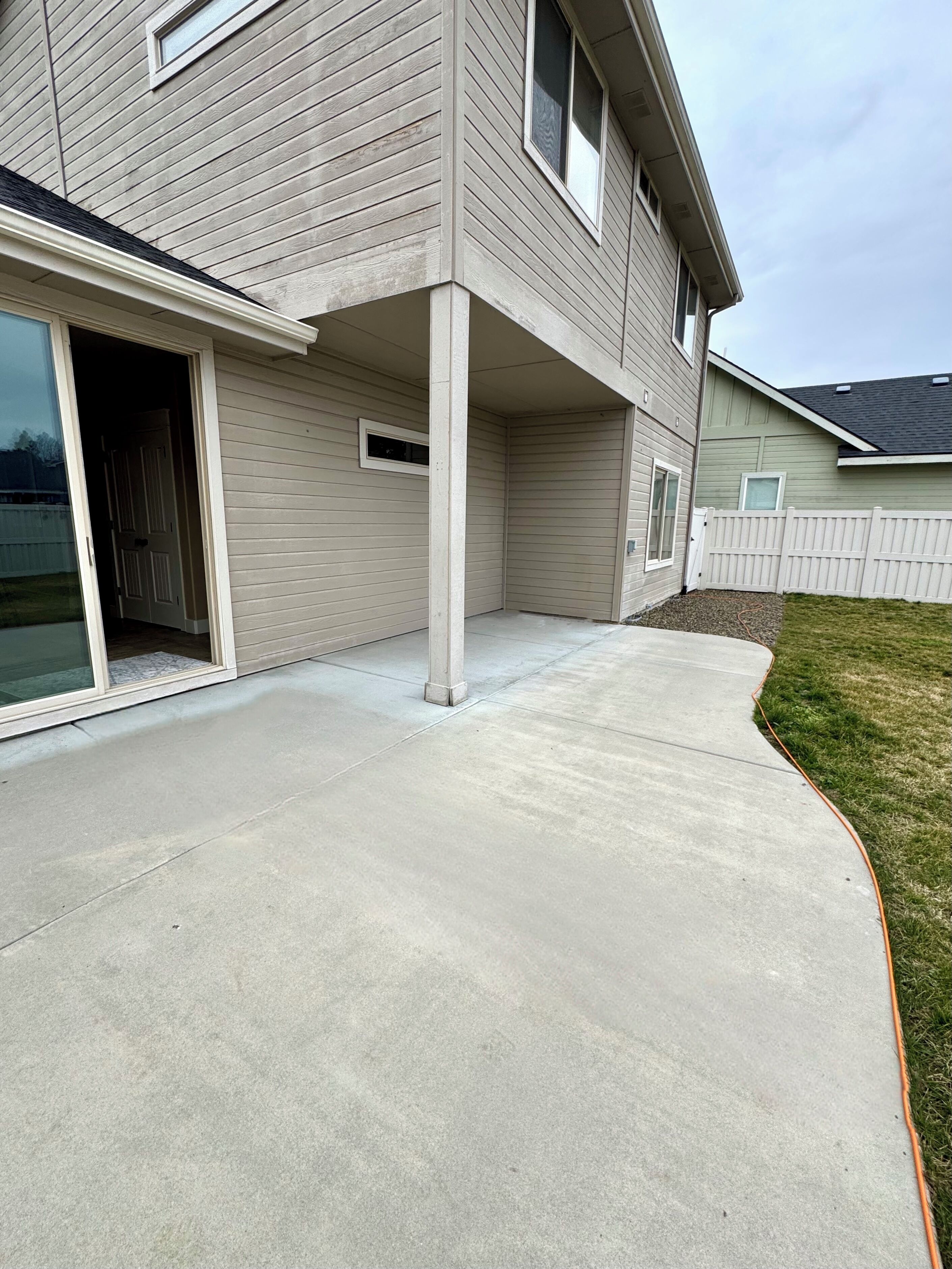 A house with a covered patio area, a sliding glass door, and a white fence.