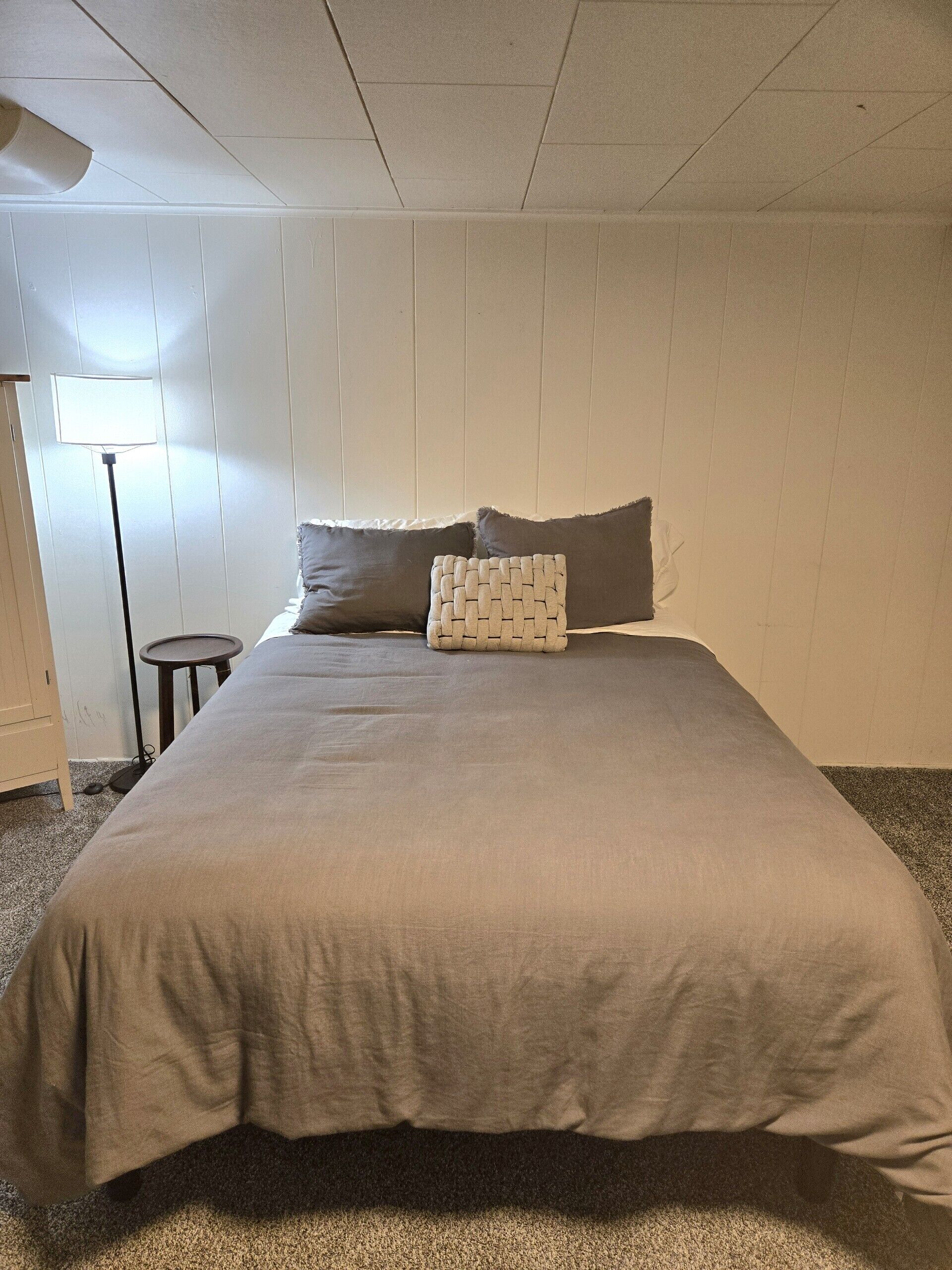 Une chambre à coucher avec un grand lit, une lampe sur pied et une petite table.