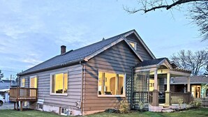 Ein zweistöckiges Haus mit einer überdachten Veranda und einem umzäunten Garten.