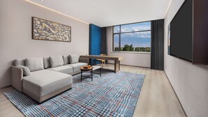 Een moderne woonkamer met een hoekbank, een salontafel en een groot raam met uitzicht.