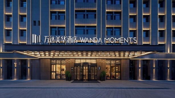 Een hotelgevel met modern ontwerp, verlichte signage en een draaideur.