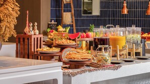 Een buffet met diverse gerechten en drankjes, een decoratieve vaas en een houten ladder op de achtergrond.