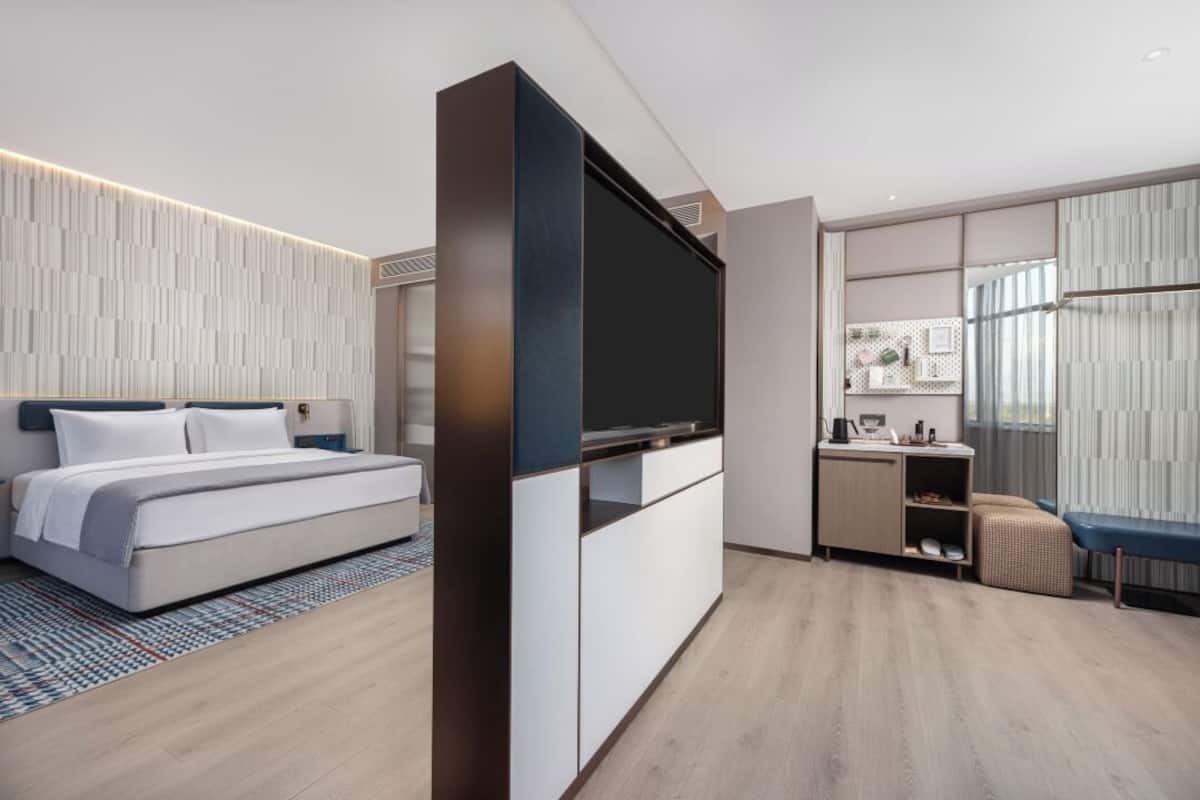 Una camera da letto moderna con un letto, una TV, una scrivania e una sedia.