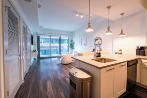 A modern kitchen with a central island, pendant lighting, and a view to a balcony. - Buckhead Serenity Skyline Retreat (Atlanta)