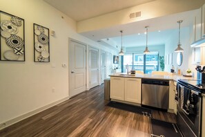 A modern kitchen with a central island, stainless steel appliances, pendant lighting, and a view to the outside. - Buckhead Serenity Skyline Retreat (Atlanta)