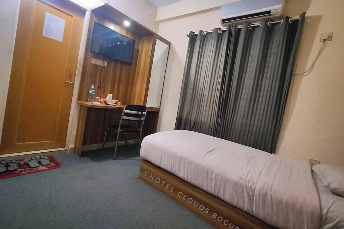 Een hotelkamer met een bed, een bureau, een stoel, een televisie en een gordijn.