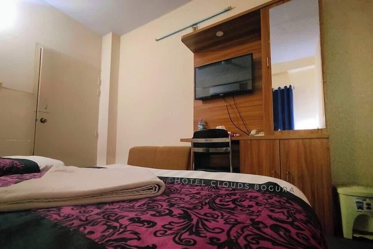 Een hotelkamer met een bed, een aan de muur bevestigde televisie, een tafeltje en een stoel.