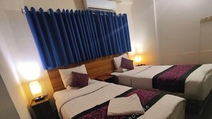 Ένα δωμάτιο ξενοδοχείου με δύο κρεβάτια, μια μπλε κουρτίνα, φωτιστικά κομοδίνου και ένα ξύλινο προσκέφαλο.