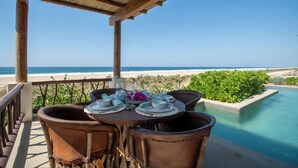 A wooden deck with a table set for two, overlooking a beach and a swimming pool. - Beach Hose with Private Pool. Casa Quinta Nayaa (El Tomatal)