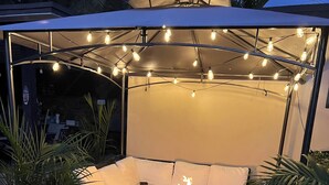 A covered outdoor seating area with a fire table, string lights, and potted plants. - 4 bath & 4 bedroom house in beautiful Pompano Beach with AC (Pompano Beach)