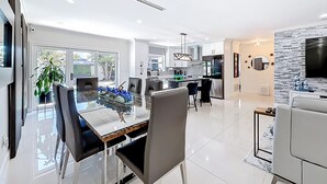 A modern kitchen with white cabinets, a black countertop, and stainless steel appliances. There is a dining area with a glass table and black chairs. - 4 bath & 4 bedroom house in beautiful Pompano Beach with AC (Pompano Beach)