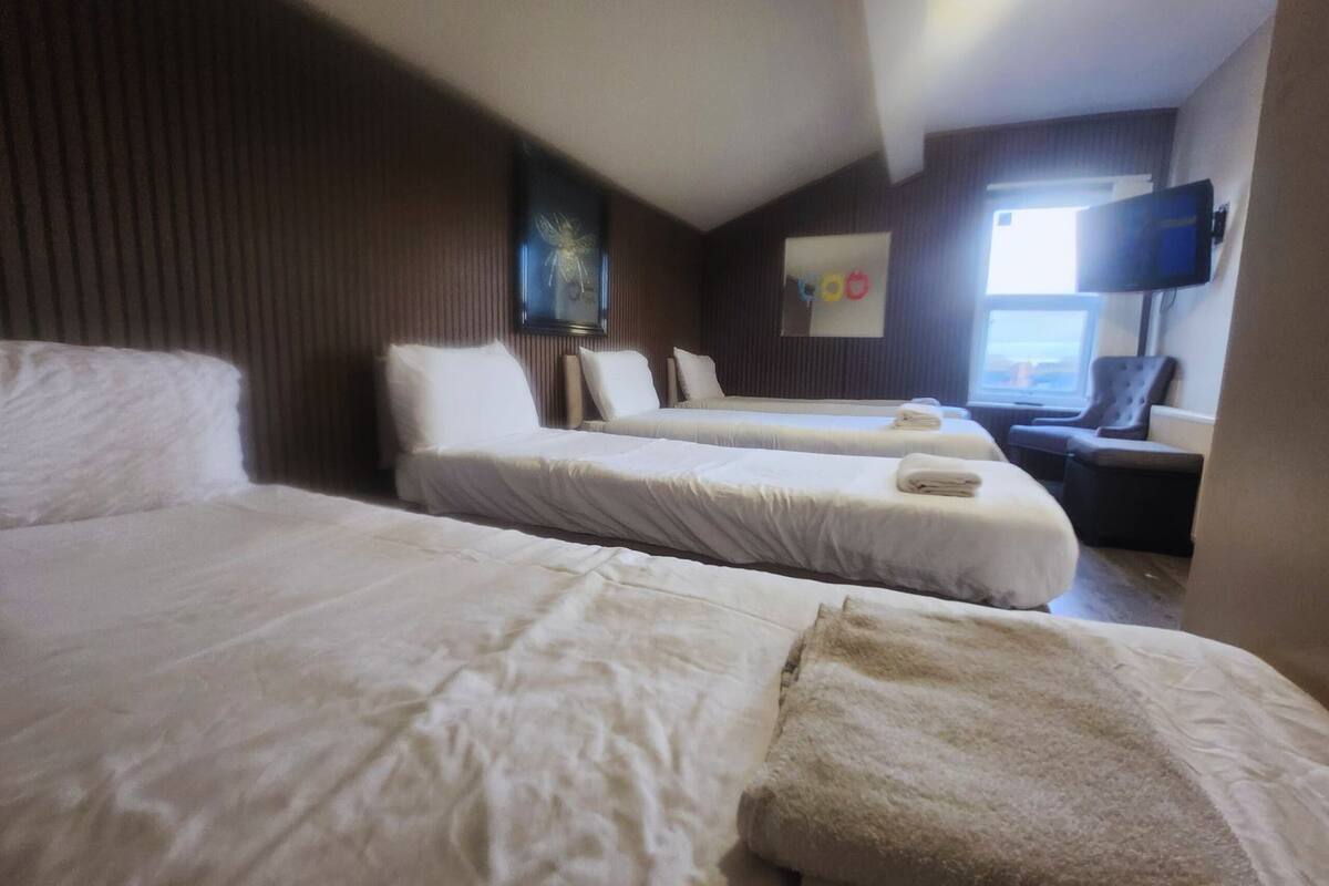 Habitación de hotel con dos camas, un televisor de pantalla plana y una ventana con vistas.