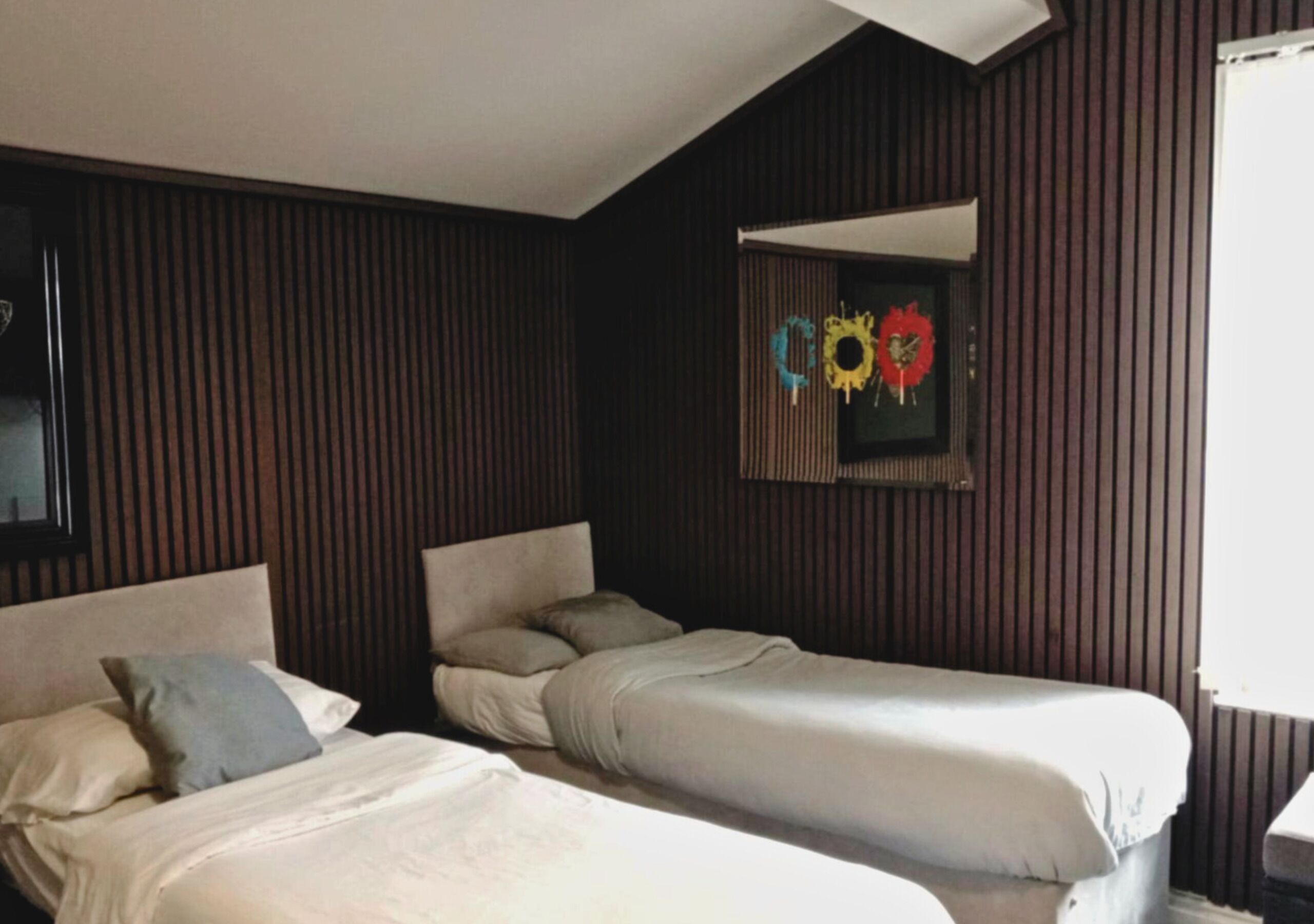 A room with two beds, wooden paneling on the walls, and a mirror above the beds.