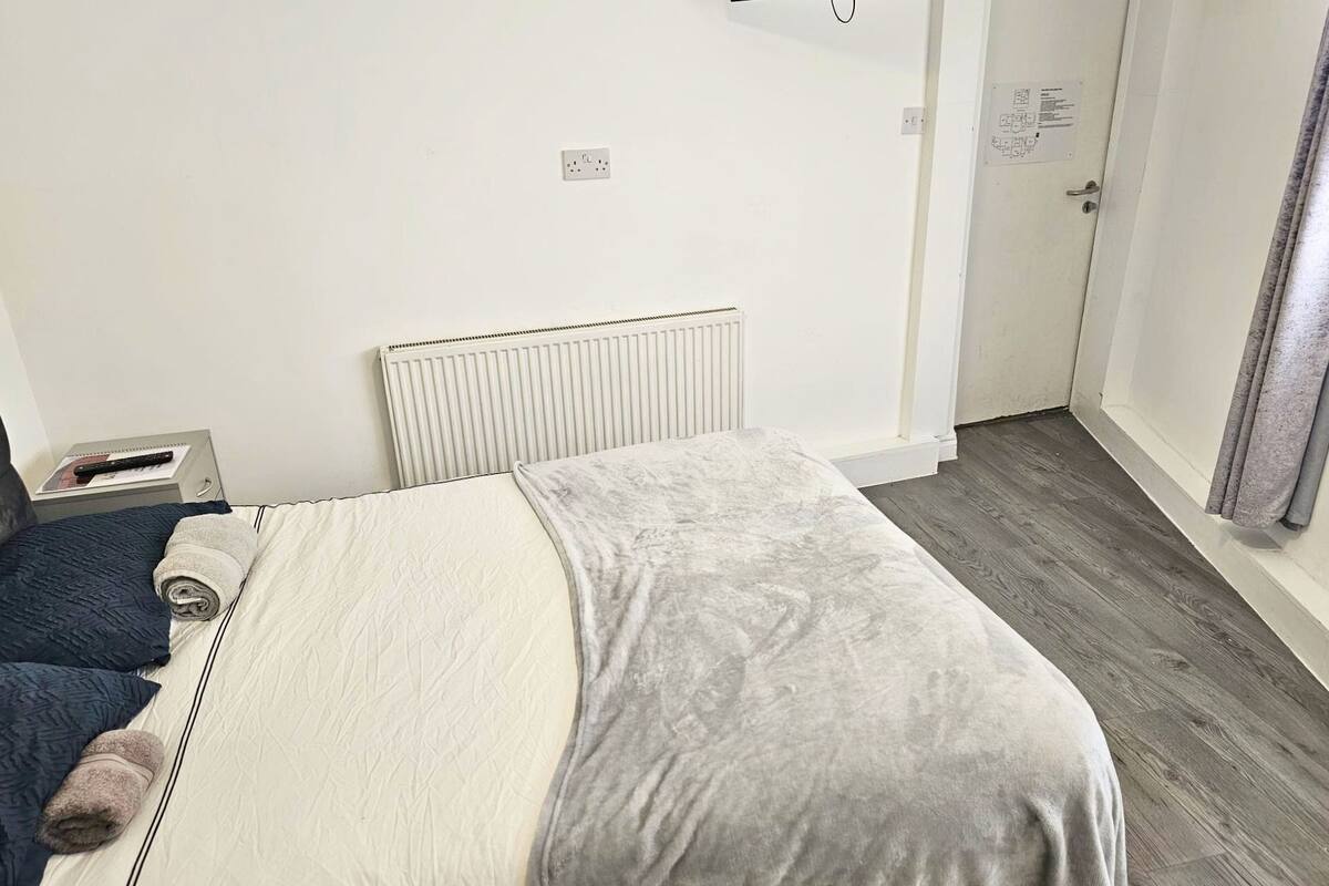 Un dormitorio con cama, un radiador, una toma de corriente y una puerta con un letrero.