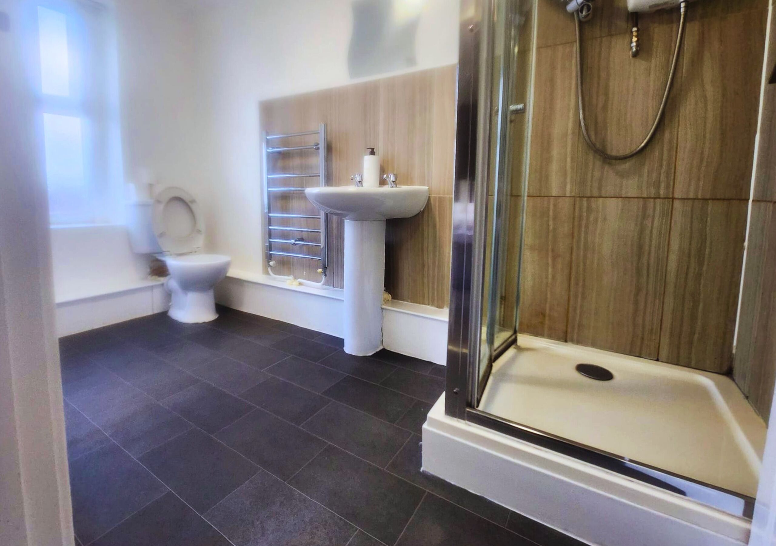 A modern bathroom with a toilet, sink, and glass-enclosed shower.
