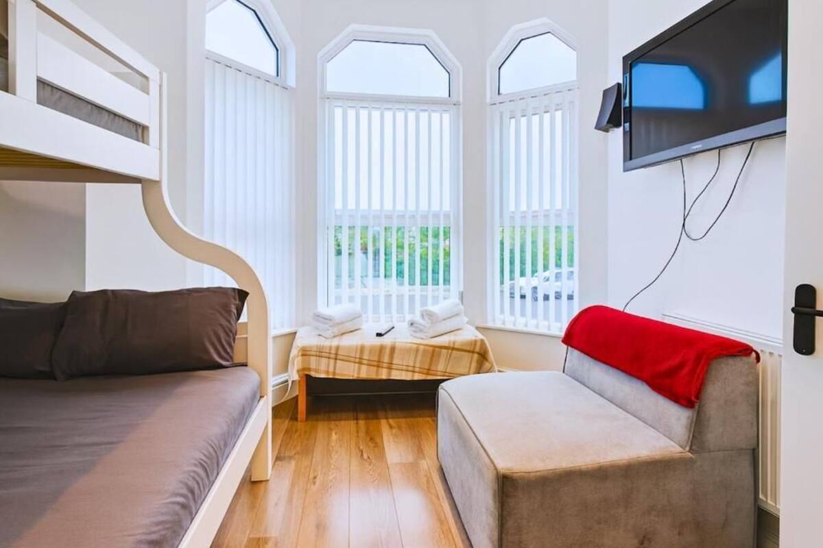 Una habitación con literas, un sofá y una televisión instalada en la pared.
