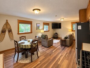 Un espacio de sala acogedor con comedor, chimenea y televisor montado en la pared.