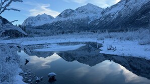 Eine friedliche Winterlandschaft mit schneebedeckten Bergen und einem stillen See, der die Umgebung spiegelt.