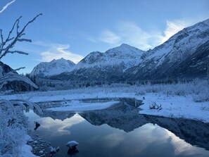 Eine friedliche Winterlandschaft mit schneebedeckten Bergen und einem stillen See, der die Umgebung spiegelt.