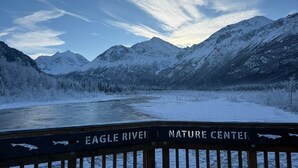 Schneegebirgslanschaft mit einem Fluss und einem Schild mit der Aufschrift 'Eagle River Nature Center'.