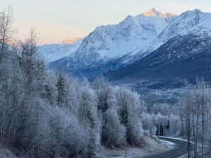 Ein verschneites Gebirge mit einer kurvenreichen Straße, die durch einen Wald führt.