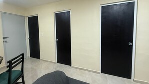 A hallway with three black doors, a green chair, and a grey sofa. - Casa Villas Amanecer (Mérida)