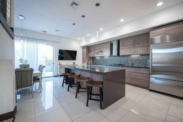 Una cocina moderna con una isla grande, electrodomésticos de acero inoxidable y un televisor de pantalla plana.