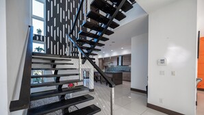 A modern staircase with black railings and a view of a kitchen area with a tiled backsplash. - Phenomenal 6-bedroom villa with infinity pool in vibrant Las Vegas (Las Vegas)