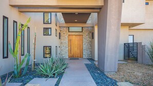 A modern building with a stone facade, a wooden door, and a pathway lined with plants and pebbles. - Phenomenal 6-bedroom villa with infinity pool in vibrant Las Vegas (Las Vegas)