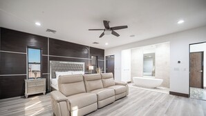 A modern living room with a beige leather sofa, a large window, a ceiling fan, and a view into the bedroom. - Phenomenal 6-bedroom villa with infinity pool in vibrant Las Vegas (Las Vegas)
