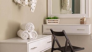 Une coiffeuse blanche avec un miroir, une chaise noire et des serviettes enroulées posées sur le dessus.