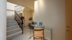 Un escalier avec une rampe en métal, une table en verre avec une chaise, et une porte dans un couloir.