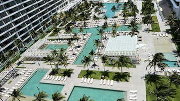 Un resort con varias piscinas, palmeras y un gran edificio.