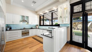 Een moderne keuken met witte kasten, een centraal eiland en uitzicht op het buiten.