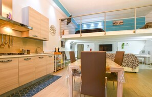 A modern kitchen with wooden cabinets, a gas stove, and a dining area with a table and chairs. - 1 bedroom cozy apartment in Partinico (Partinico)