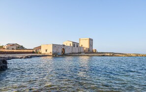 A coastal building with a prominent tower, situated near a body of water. - 1 bedroom cozy apartment in Partinico (Partinico)