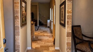 A hallway with stone flooring, an archway, and a chair.
