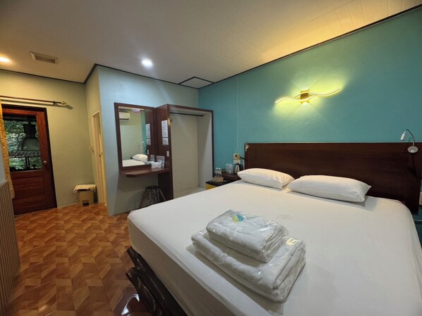 Une chambre d’hôtel comprenant un lit, une table de chevet, un miroir, une porte et un luminaire fixé au mur.