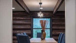 A dining area with a wooden table, blue chairs, and a vase with reeds. - Rainier Timber Retreat • Hot Tub & Sauna • Forest Deck on 5 Acres (Wilkeson)
