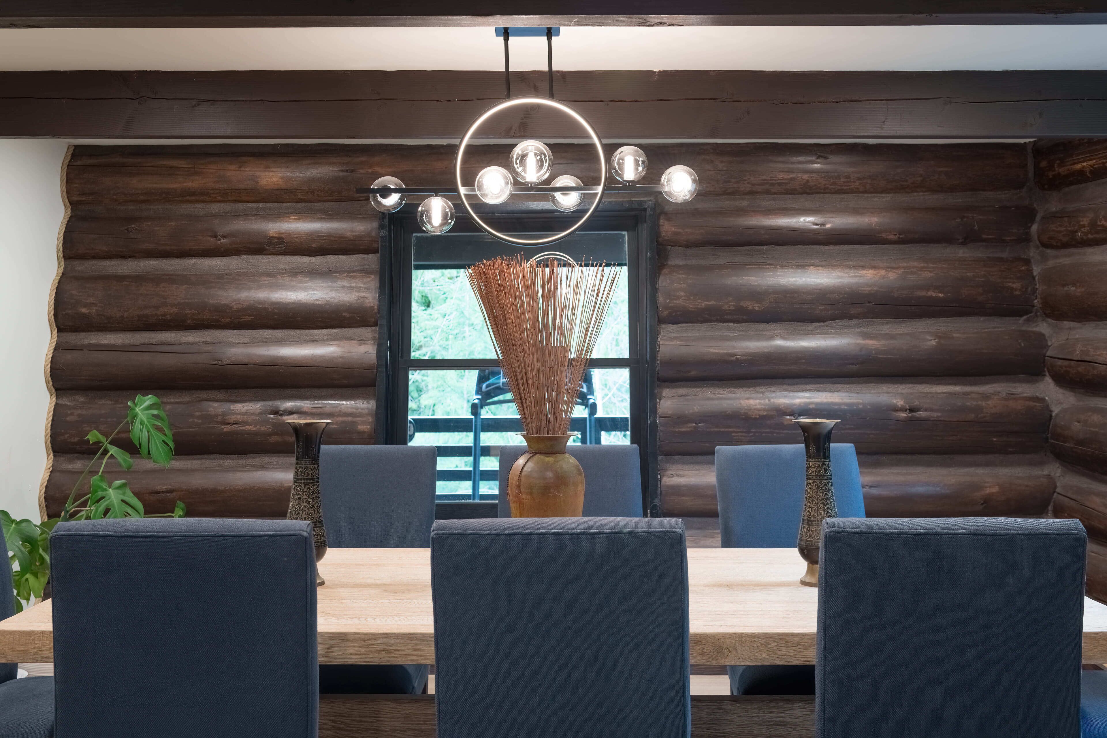 Un coin repas avec un mur en rondins de bois, une table en bois et des chaises à revêtement bleu.