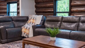A log cabin interior with two leather sofas, a wooden coffee table, and a plant. - Rainier Timber Retreat • Hot Tub & Sauna • Forest Deck on 5 Acres (Wilkeson)
