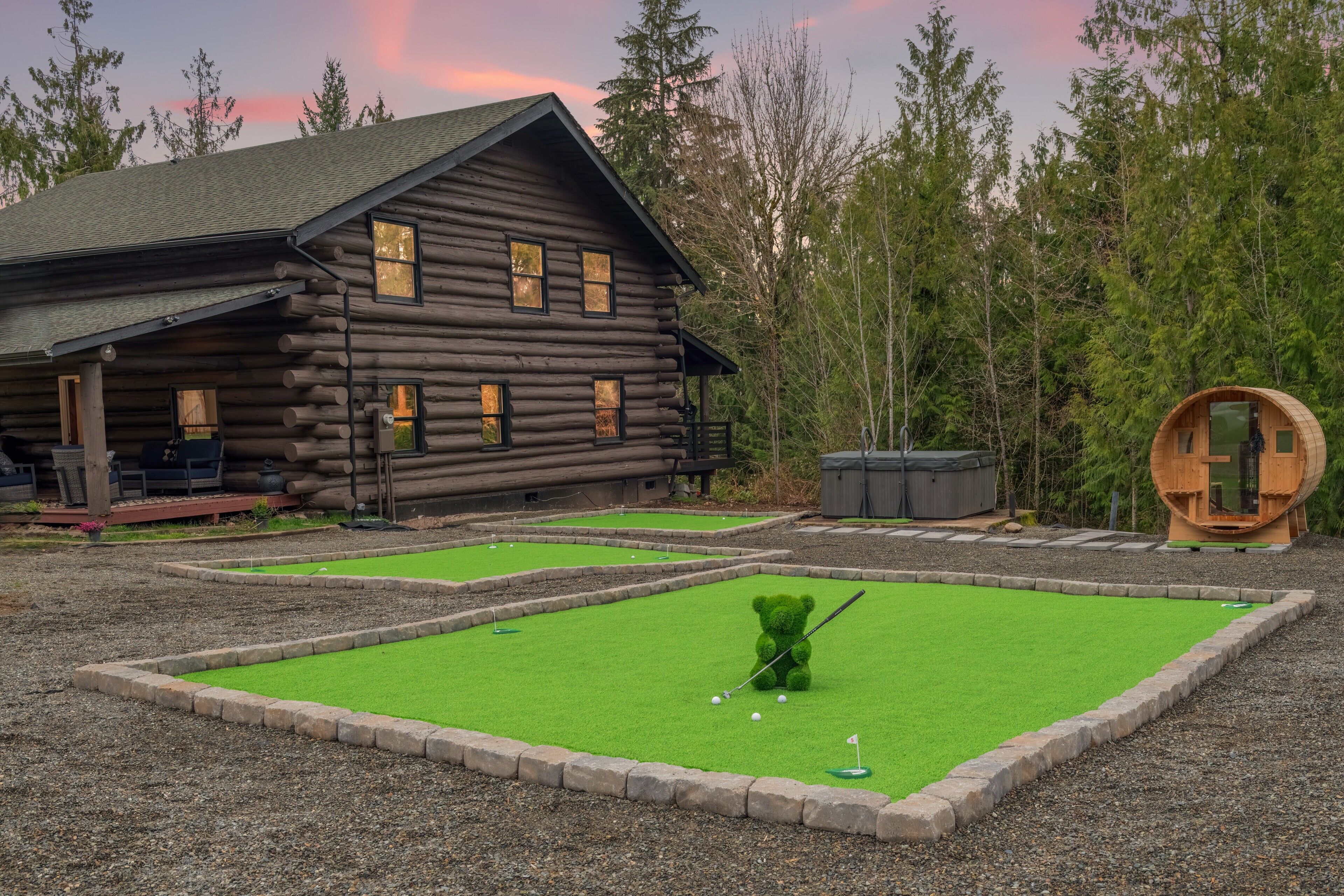 Una cabaña de troncos con un pequeño campo de práctica de golf y un barril de madera.