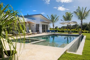 Uma casa moderna com piscina, móveis de exterior e palmeiras.