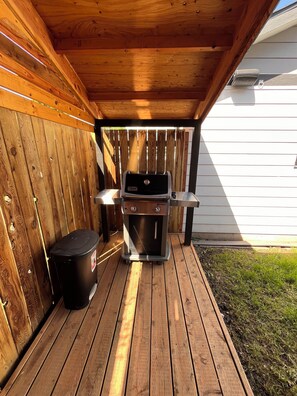 A wooden deck with a barbecue grill and a trash can. - Comfortable 4-bedroom house in a peaceful neighborhood with Backyard Patio (Millwood)